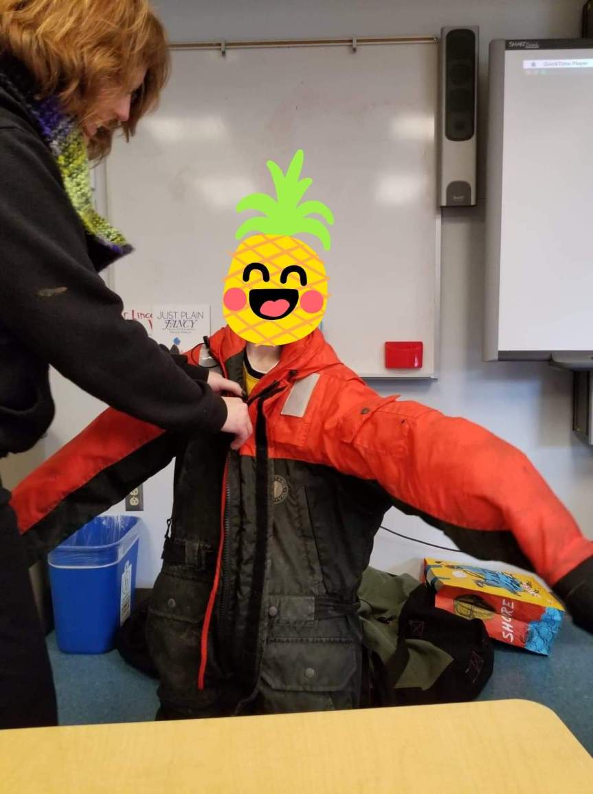 Helping a 9yr old into a polar work suit. He looks warm. Photo by Kathy Mosing Seeman